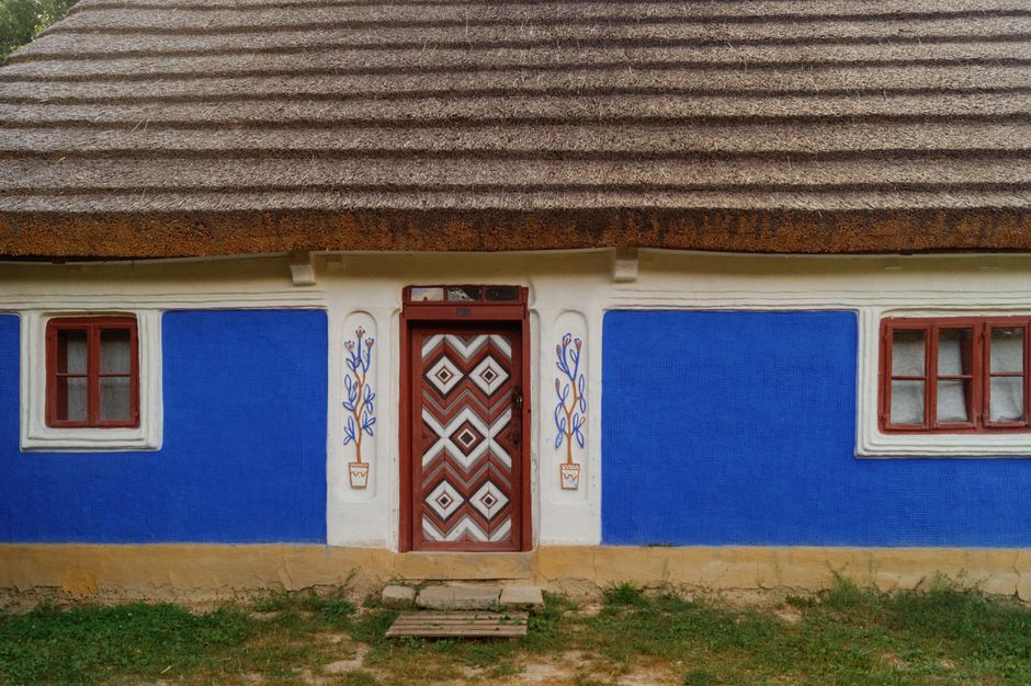 Charming traditional Ukrainian mud hut with vibrant blue walls and thatched roof in Kyiv open air museum.